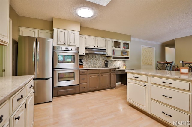 1989 Dogwood Trl, Collinsville, IL 62234 - kitchen featuring appliances with stainless steel finishes, a textured ceiling, backsplash, under cabinet range hood, and light wood-type flooring