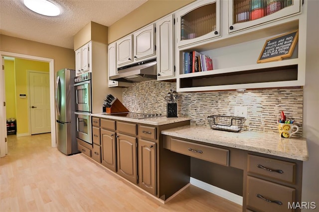 1989 Dogwood Trl, Collinsville, IL 62234 - kitchen with appliances with stainless steel finishes, under cabinet range hood, light wood finished floors, backsplash, and a textured ceiling