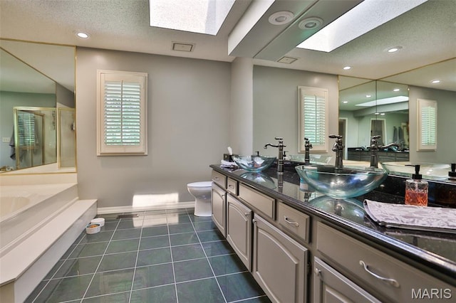 1989 Dogwood Trl, Collinsville, IL 62234 - full bathroom featuring a skylight, double vanity, toilet, a stall shower, and a garden tub