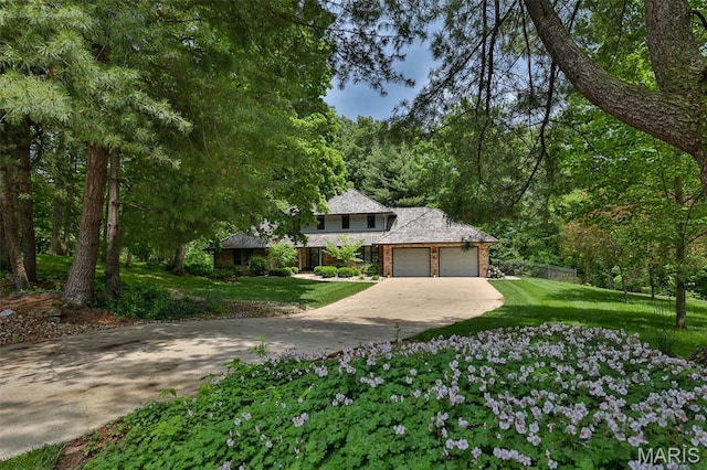 1989 Dogwood Trl, Collinsville, IL 62234 - view of front facade featuring concrete driveway, a garage, a front yard, brick siding, and a forest view