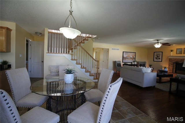 dining area featuring stairs, ceiling fan, wood finished floors, and a fireplace