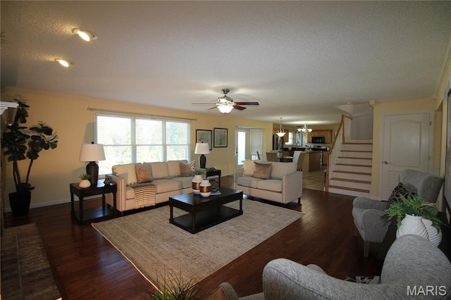 living room featuring stairs, a ceiling fan, a textured ceiling, ornamental molding, and baseboards