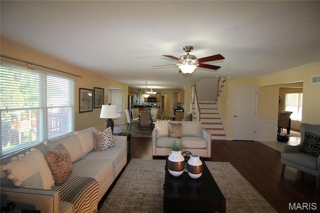 living room featuring wood finished floors, stairs, a chandelier, a textured ceiling, and ornamental molding