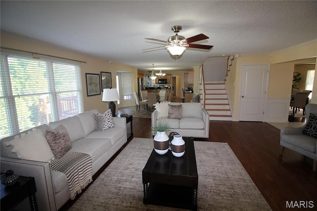 living room with wood finished floors, stairway, a chandelier, a ceiling fan, and a textured ceiling