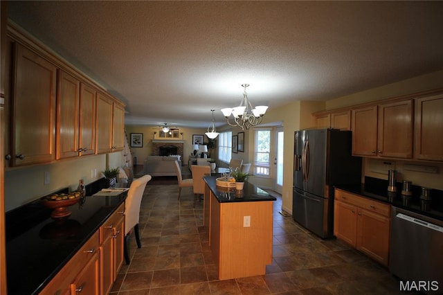 kitchen with appliances with stainless steel finishes, dark countertops, a chandelier, a kitchen island, and open floor plan