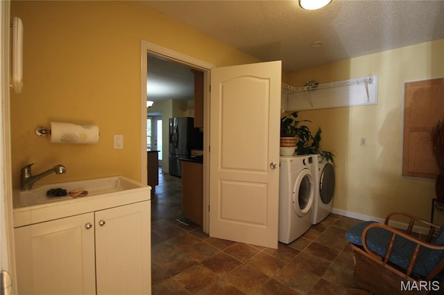 washroom featuring washer and clothes dryer, a textured ceiling, and baseboards