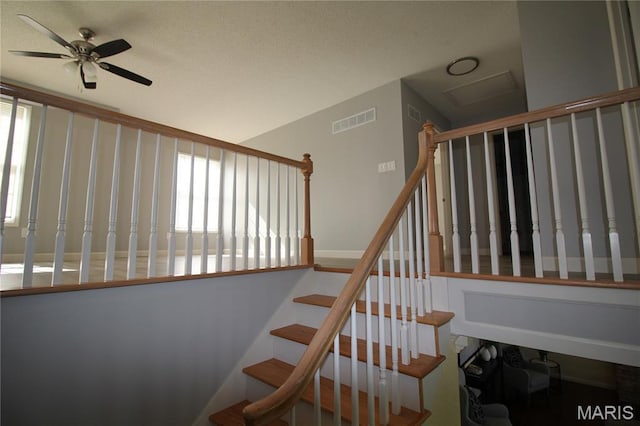 stairs featuring a ceiling fan