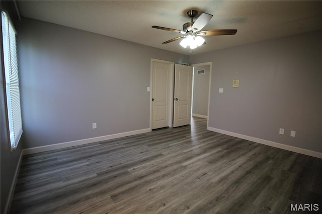empty room with a ceiling fan, dark wood finished floors, and baseboards