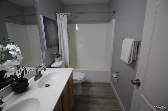 bathroom with wood finished floors, toilet, shower / bathtub combination with curtain, double vanity, and baseboards