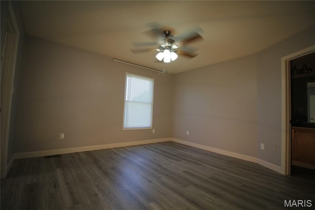 spare room featuring a ceiling fan, dark wood-style floors, and baseboards