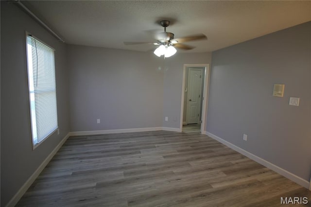 spare room featuring ceiling fan, healthy amount of natural light, wood finished floors, and baseboards