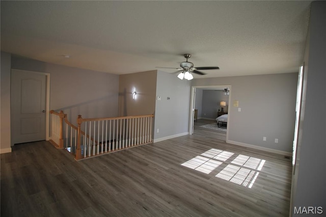 unfurnished room with a ceiling fan, wood finished floors, and baseboards