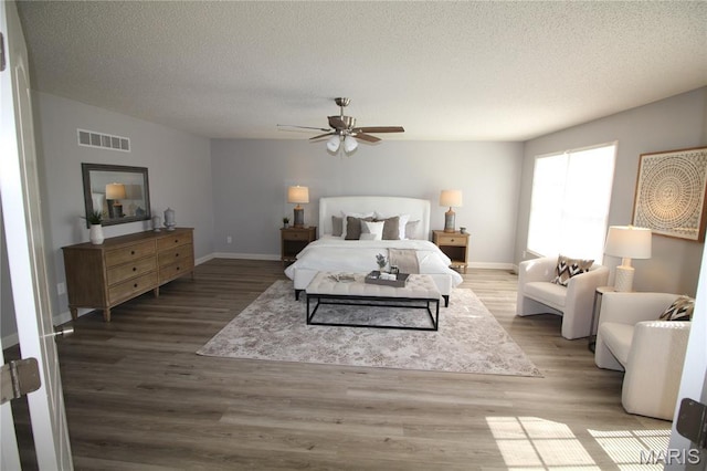 bedroom featuring a textured ceiling, wood finished floors, baseboards, and a ceiling fan