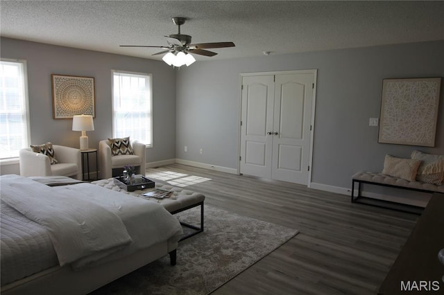 bedroom featuring wood finished floors, baseboards, a textured ceiling, a closet, and a ceiling fan