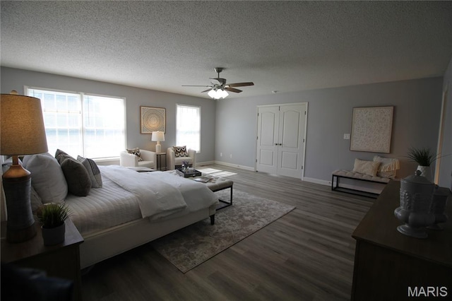 bedroom featuring a textured ceiling, multiple windows, baseboards, wood finished floors, and ceiling fan