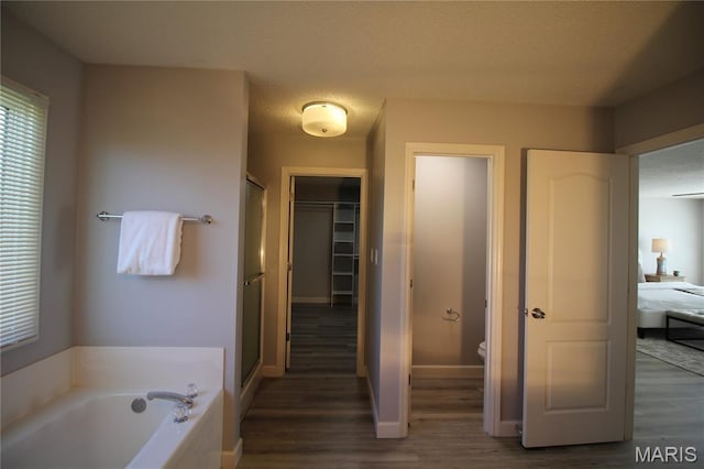 bathroom with wood finished floors, a stall shower, a garden tub, and toilet