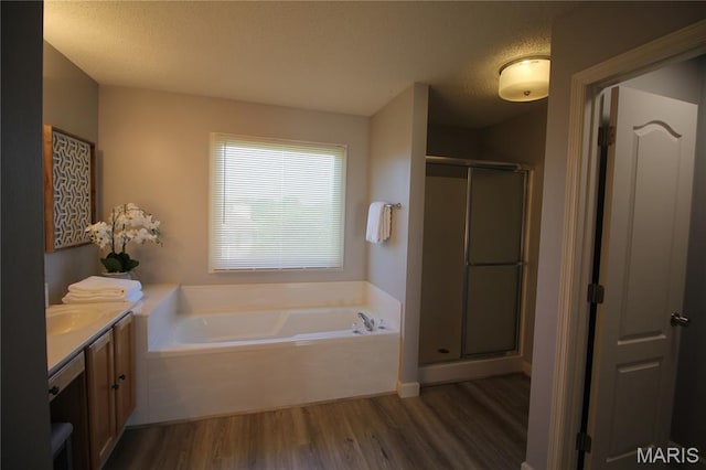 bathroom featuring wood finished floors, a stall shower, vanity, a bath, and a textured ceiling