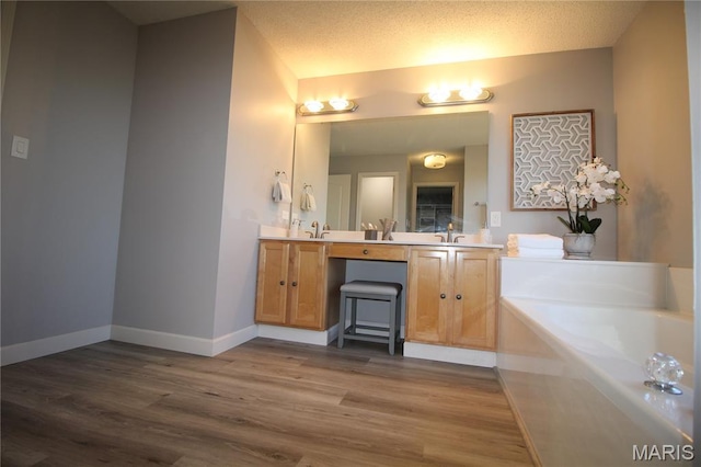 full bathroom with a garden tub, wood finished floors, double vanity, and baseboards