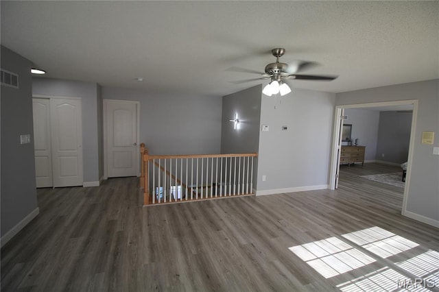 empty room with ceiling fan, wood finished floors, and baseboards