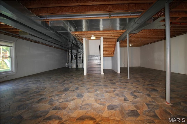 below grade area featuring stairs, stone finish floors, and water heater