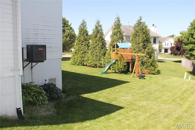 view of grassy yard with a playground and central air condition unit