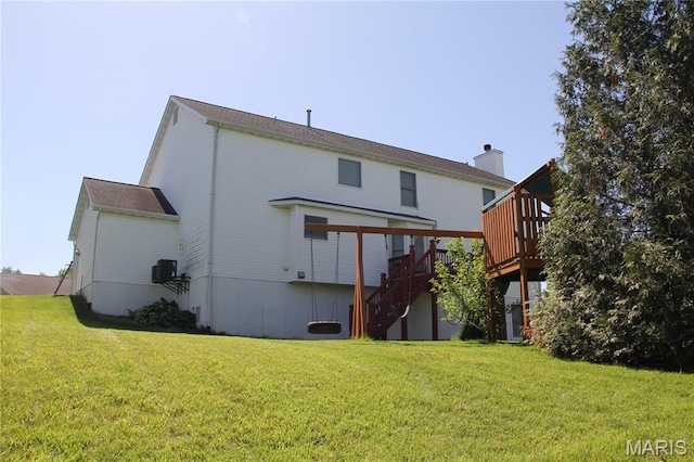 back of house featuring stairway, a deck, and a yard