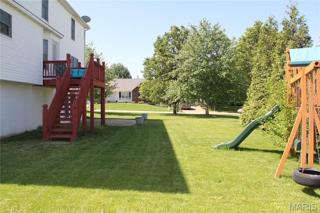 view of green lawn featuring a playground, stairs, and a deck
