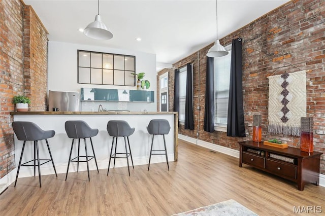 2713 Utah St, Saint Louis, MO 63118 - kitchen with stainless steel fridge, brick wall, wood finished floors, pendant lighting, and baseboards