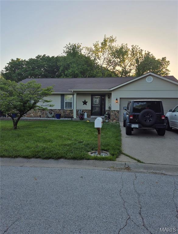 single story home featuring an attached garage, a lawn, and concrete driveway