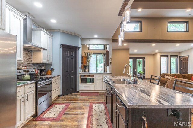 732 N Main St, Poplar Bluff, MO 63901 - kitchen featuring stainless steel appliances, wall chimney exhaust hood, a sink, a center island with sink, and wood finished floors