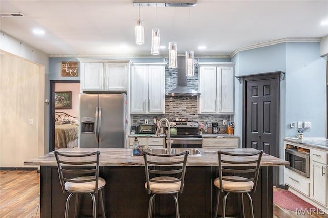 732 N Main St, Poplar Bluff, MO 63901 - kitchen featuring stainless steel appliances, wall chimney range hood, tasteful backsplash, a kitchen breakfast bar, and pendant lighting