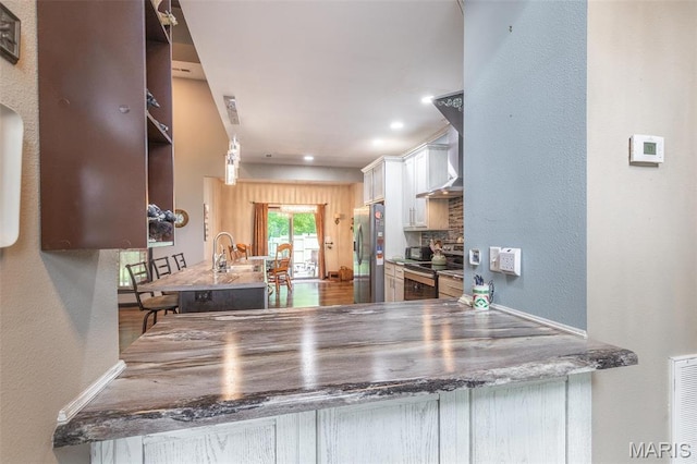 732 N Main St, Poplar Bluff, MO 63901 - kitchen featuring appliances with stainless steel finishes, white cabinets, a textured wall, wall chimney exhaust hood, and tasteful backsplash