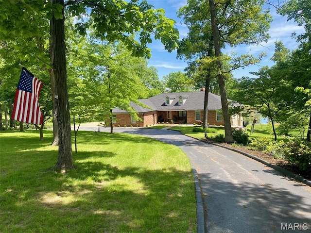 view of front of home featuring a front lawn, brick siding, and a chimney