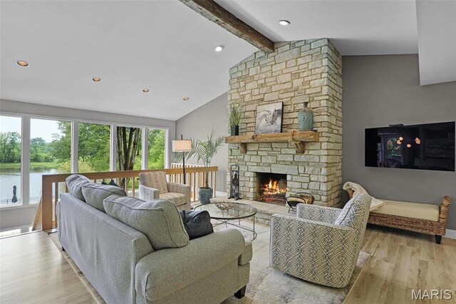 living area with light wood-type flooring, recessed lighting, a fireplace, and a water view