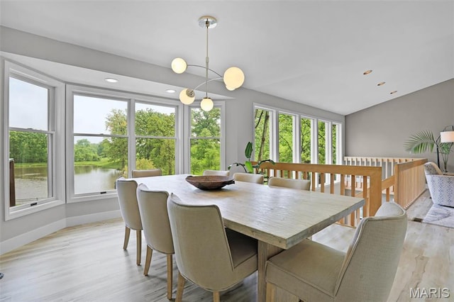 dining area with light wood finished floors, baseboards, a water view, and recessed lighting