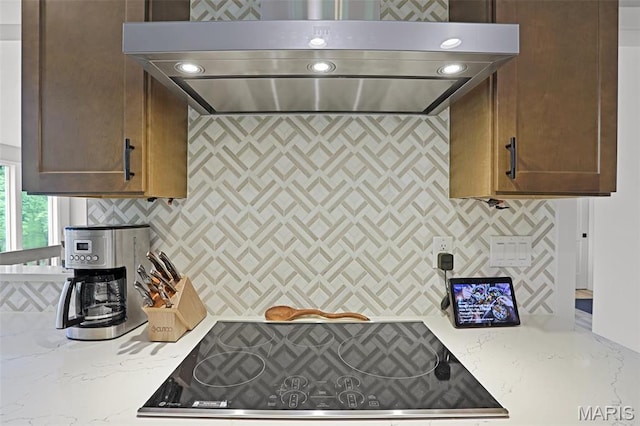 kitchen with extractor fan, decorative backsplash, black electric cooktop, and light stone counters