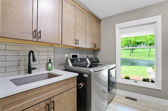 laundry room with cabinet space, washer and dryer, baseboards, and wood finished floors