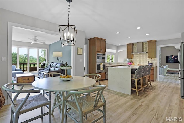 dining area featuring light wood-type flooring, a ceiling fan, recessed lighting, and a chandelier
