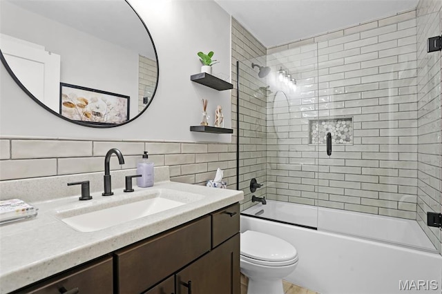 bathroom featuring tile walls, toilet, shower / bath combination with glass door, and vanity