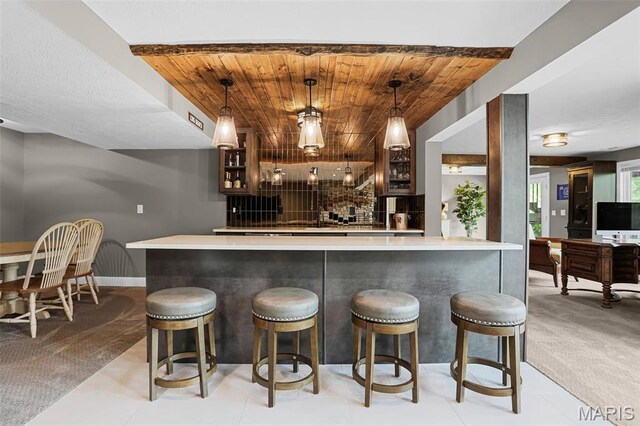 indoor wet bar featuring wooden ceiling, decorative light fixtures, baseboards, and light colored carpet