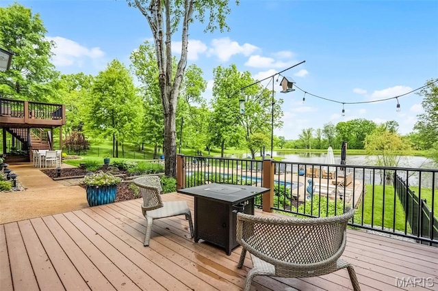 wooden terrace featuring a water view, stairway, and view of wooded area
