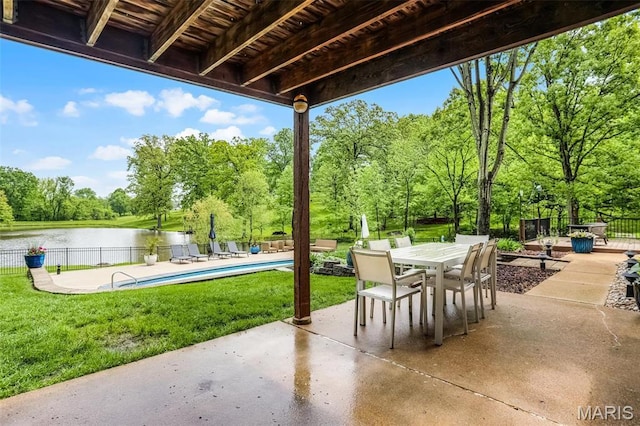 view of patio with view of wooded area, a water view, and outdoor dining space