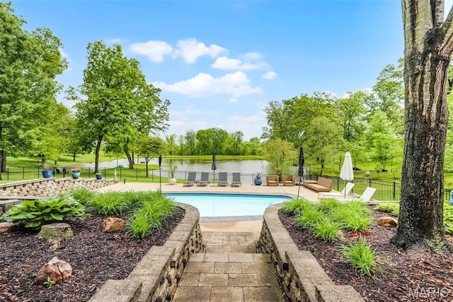 view of pool featuring fence, a patio area, and view of scattered trees