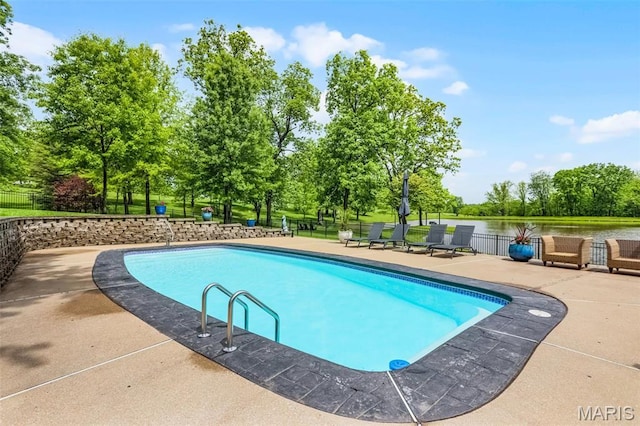 view of pool featuring fence, view of wooded area, and a patio area