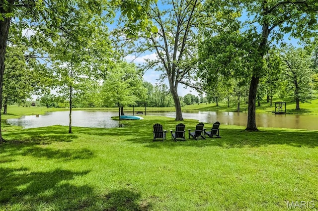 view of community with a lawn, a water view, and view of scattered trees