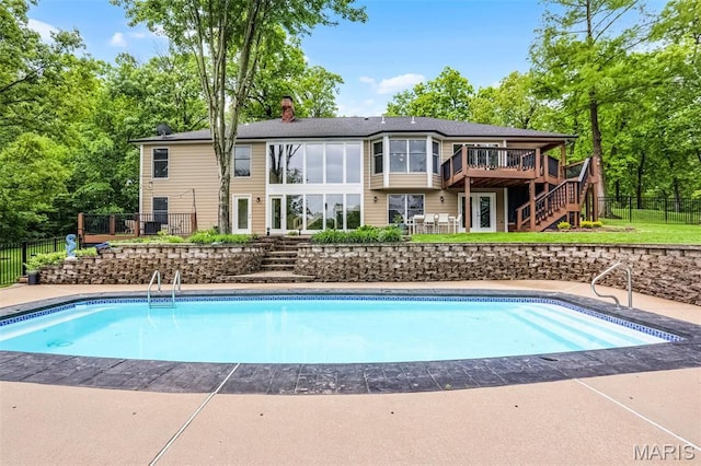 view of pool featuring stairway, a deck, fence, and view of scattered trees