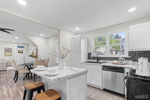 7211 Kensington Ave, Maplewood, MO 63143 - kitchen with dishwasher, gas range oven, a sink, a breakfast bar, and tasteful backsplash
