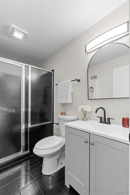 7211 Kensington Ave, Maplewood, MO 63143 - full bath featuring vanity, toilet, a shower stall, and tile patterned flooring