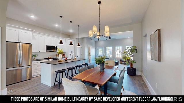 3229 Portis Ave, Saint Louis, MO 63116 - dining space with light wood-style floors, a chandelier, recessed lighting, and baseboards