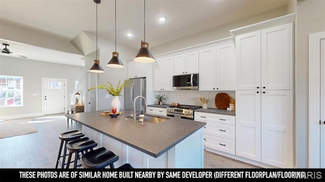 3229 Portis Ave, Saint Louis, MO 63116 - kitchen with appliances with stainless steel finishes, a sink, dark countertops, a kitchen island with sink, and backsplash